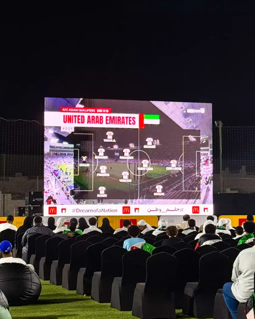 Large outdoor LED screen displaying a football match at a sports event